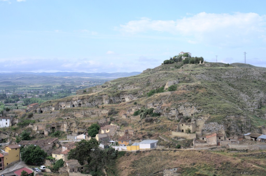 Montaña agujereada por cuevas con la ermita en la cima.