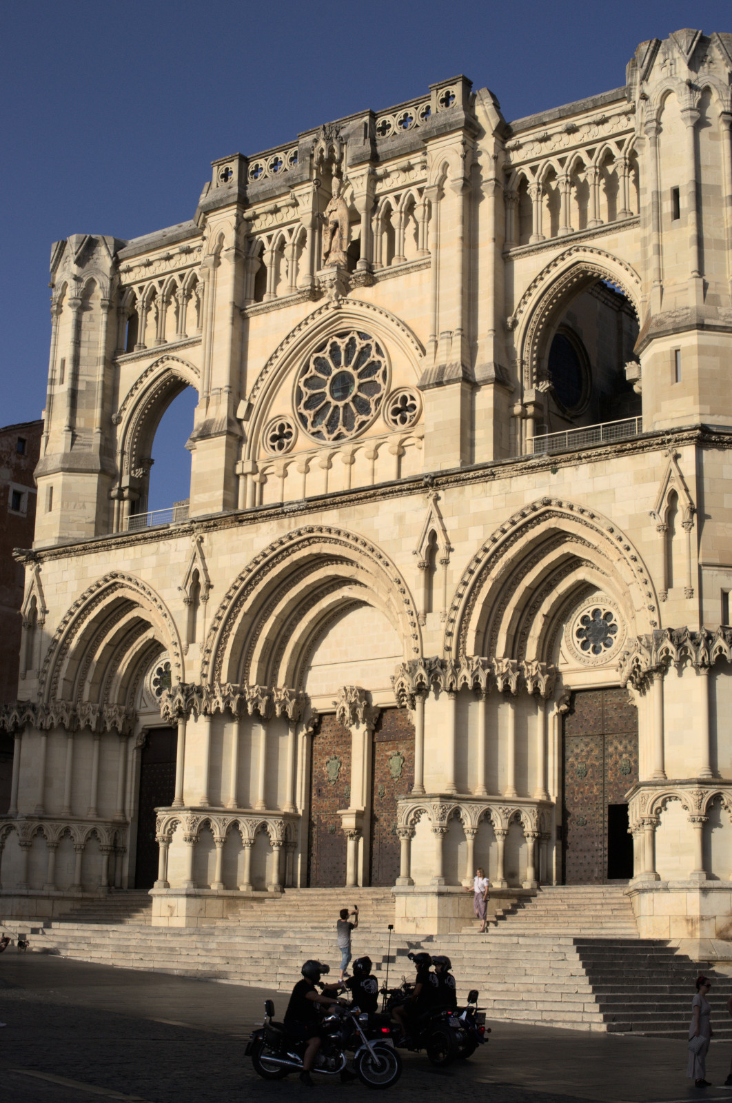 Освещённый вечерним солнцем собор, мотоциклисты перед ним