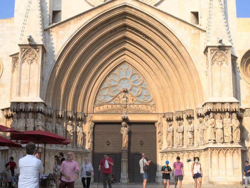 Готический портал со статуями святых. Всё освещается вечерним солнцем.