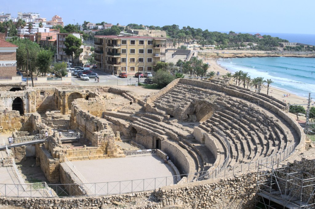 Руины амфитеатра; за ними — современные здания; справа — море