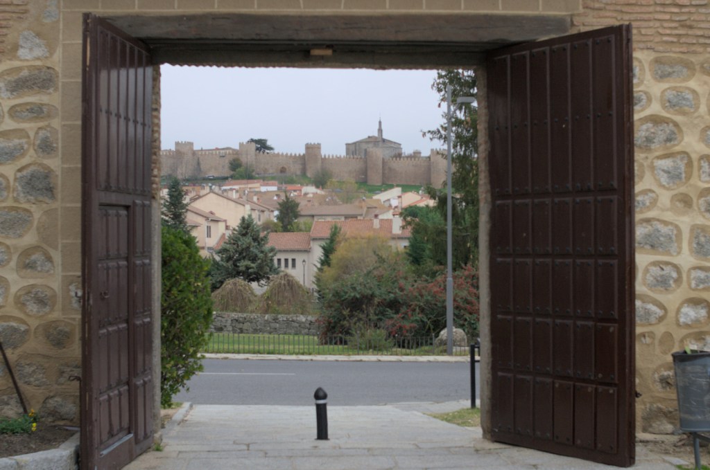 В распахнутые ворота монастыря виднеется городская стена Авилы и пять её башен