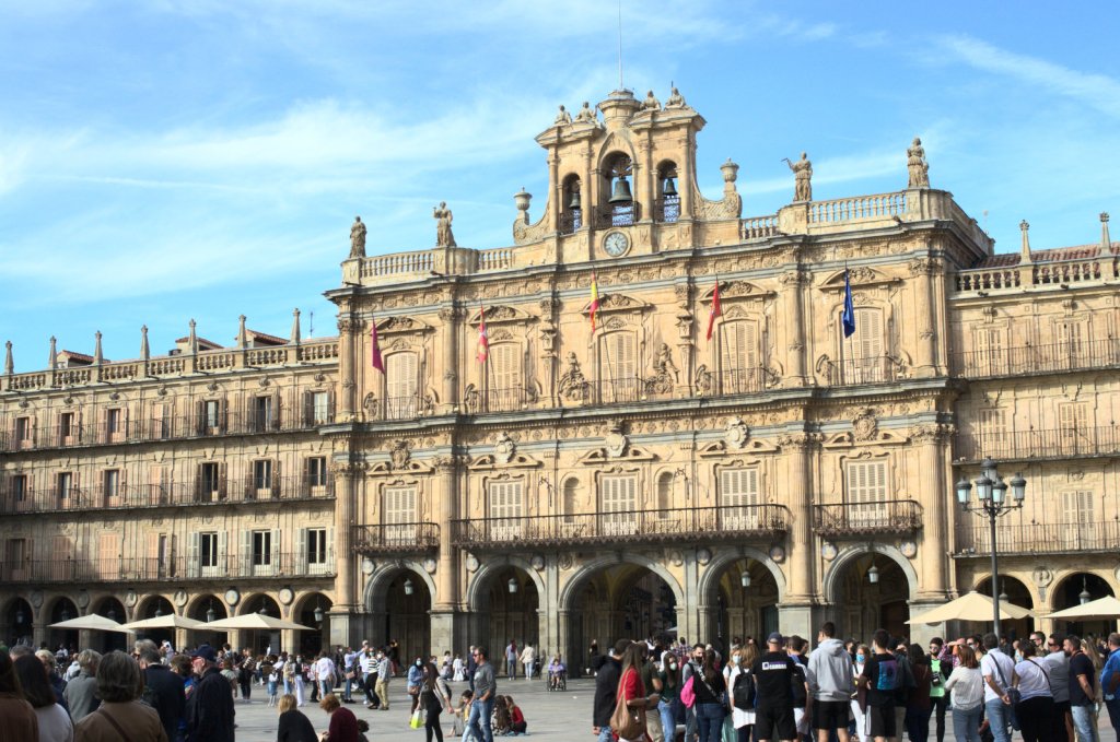 Фасад здания, возвышающегося над площадью, заполненной людьми