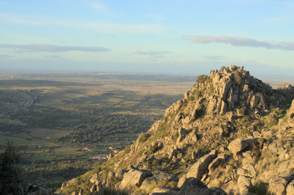 Ближние скалы и далёкая равнина, освещённые вечерним солнцем