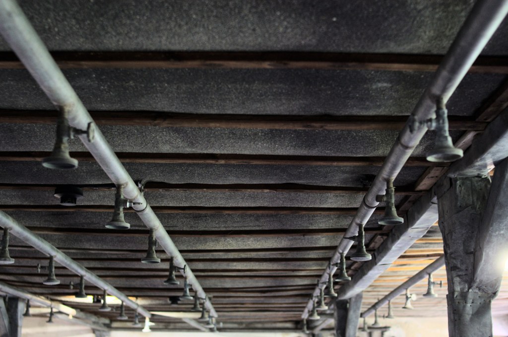 Трубы с душевыми распылителями на потолке барака