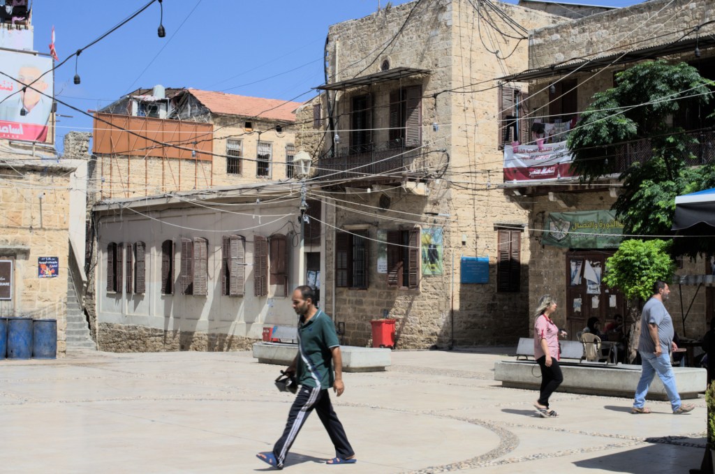 Прохожие на залитой солнцем площади со старинными домами