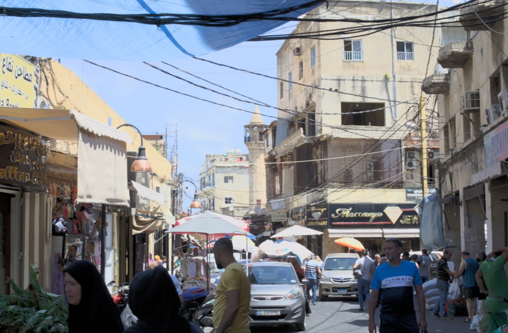 Улица с магазинами и прилавками, виден минарет мечети