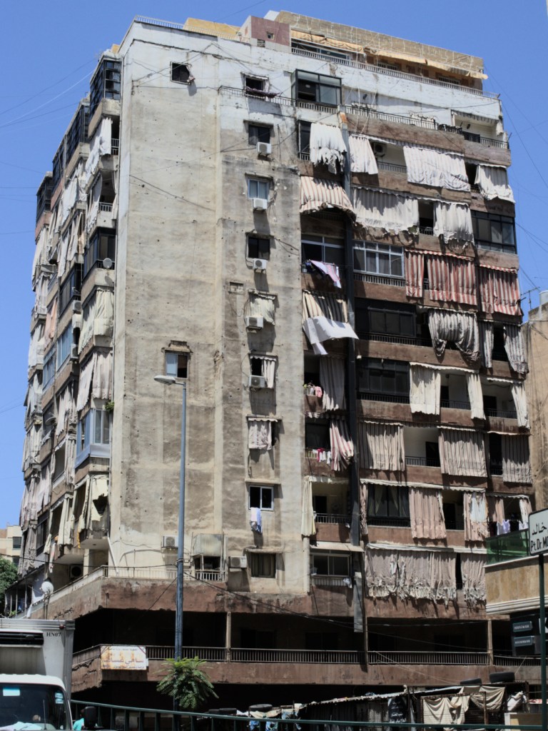 Десятиэтажный дом. Балконы и окна завешаны большими покрывалами