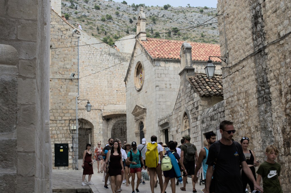 Люди идут по улице между каменных зданий