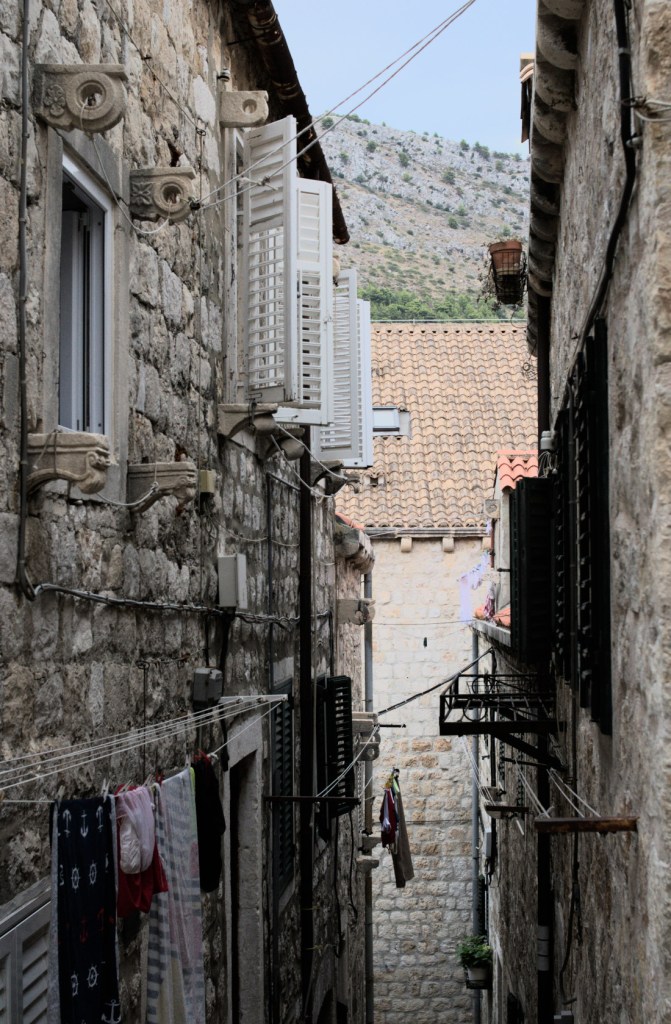 Открытые ставни, висящее бельё, сквозь переулок виднеется вершина горы