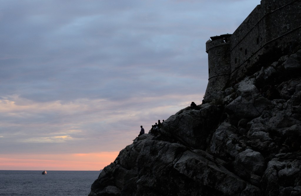 Очертания городской стены и утёса на фоне красного края неба