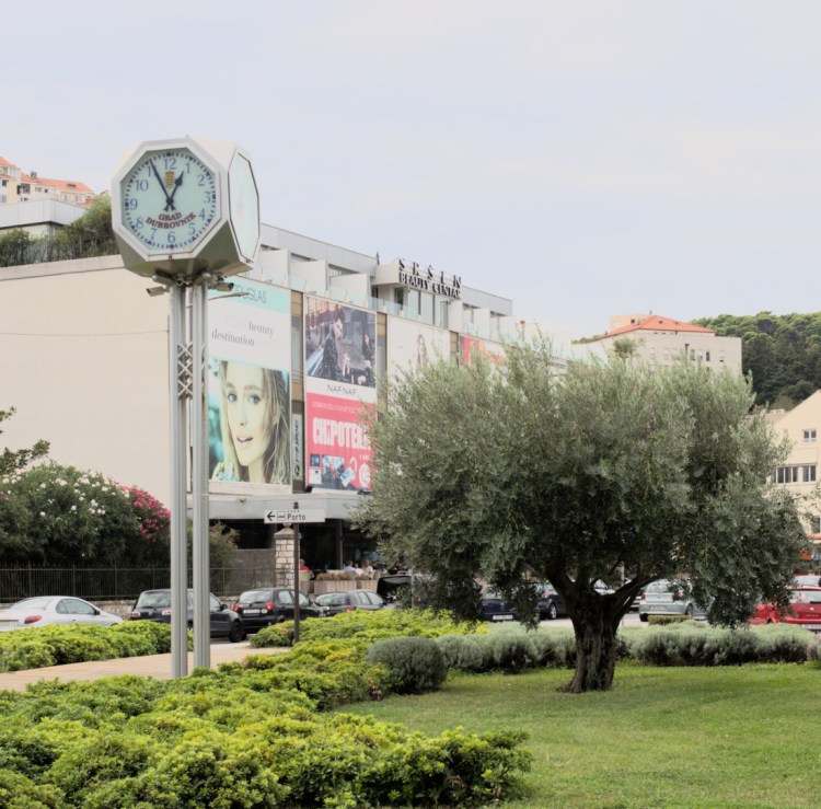 Стрелочные часы перед зданием с рекламой