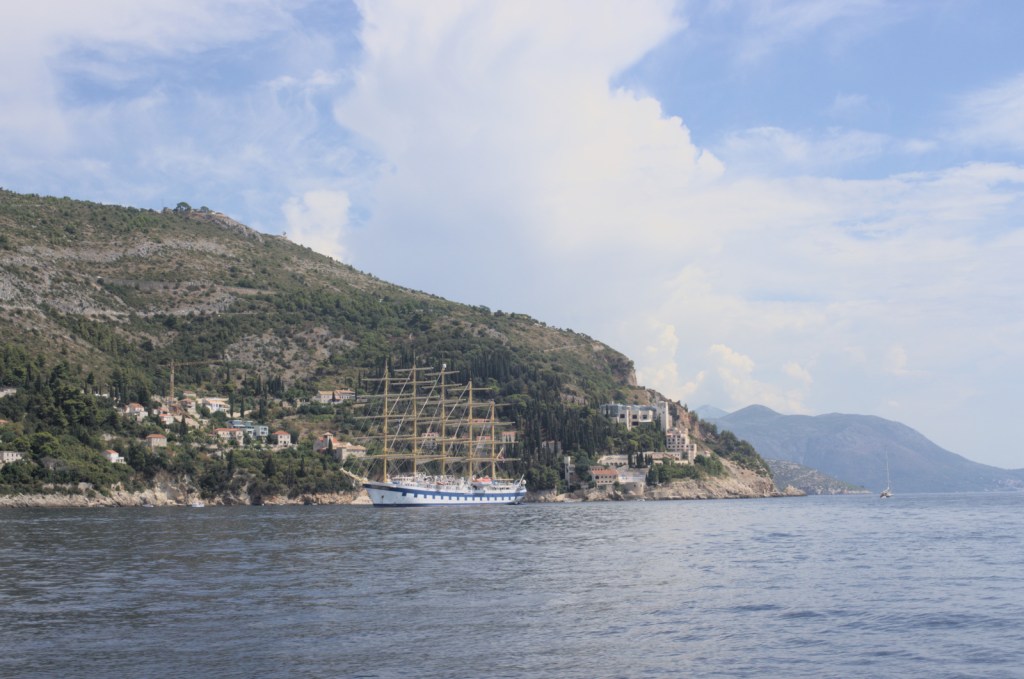 Прогулочный парусник в море перед высоким берегом