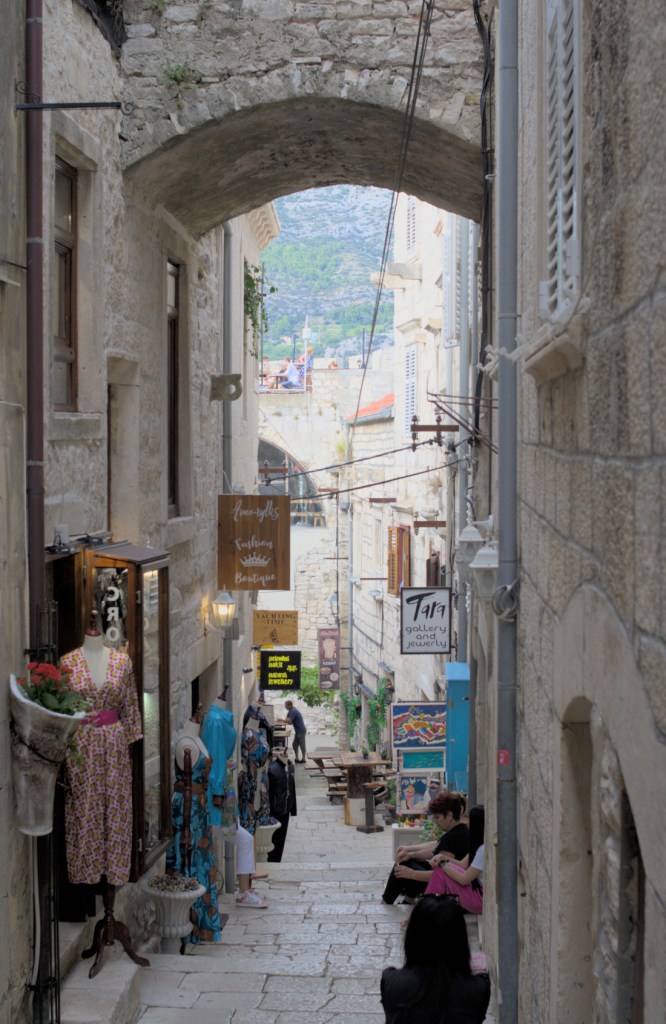 Переулок со ступеньками и аркой, по его сторонам магазины