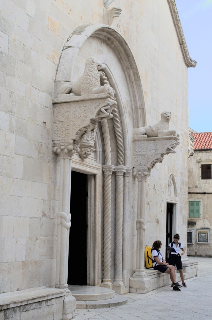 Вход в белокаменное здание, над капителями колонн скульптурные львы