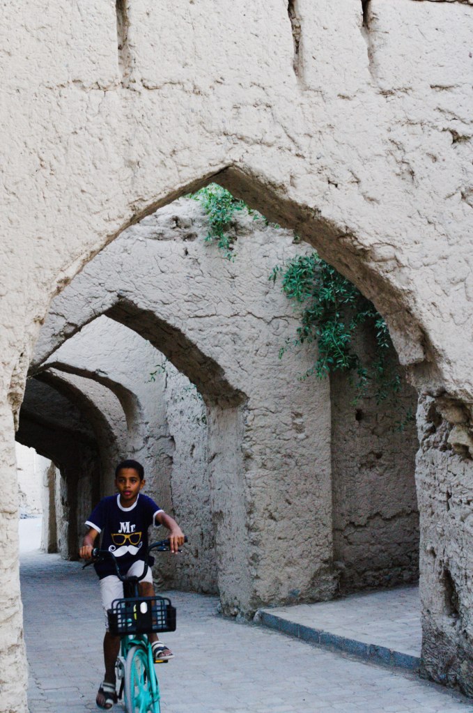 Мальчик проезжает на велосипеде через своды старинных ворот