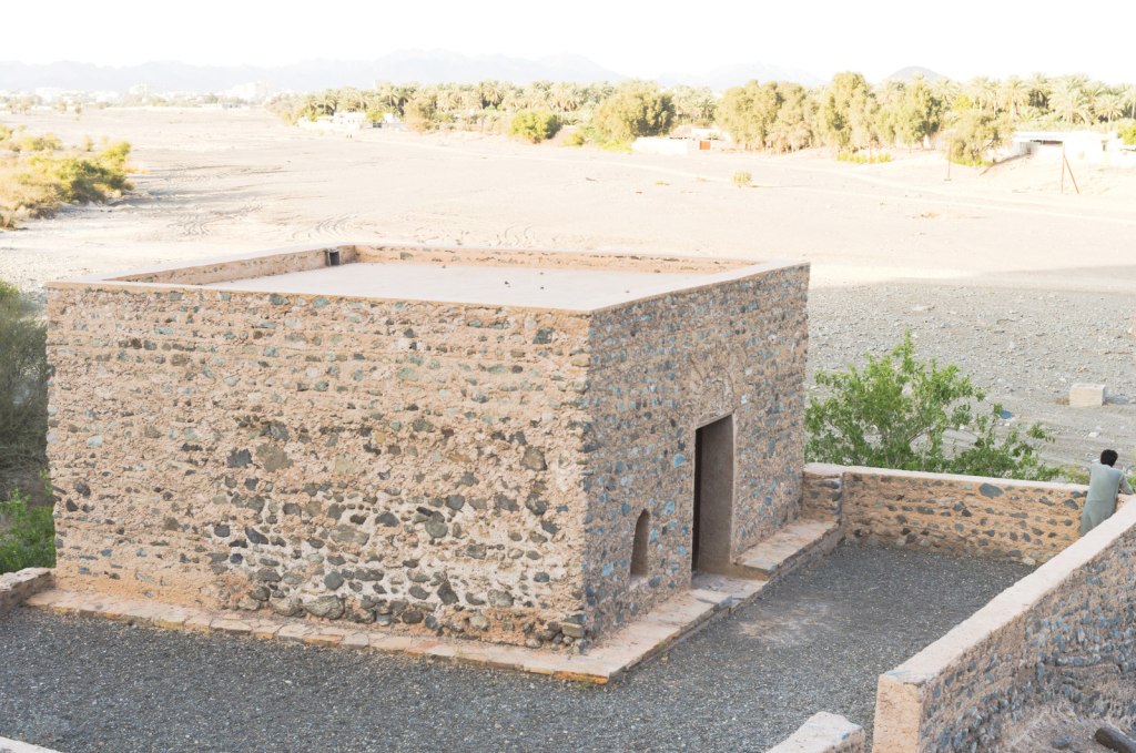 Простое каменное здание мечети на фоне сухого русла