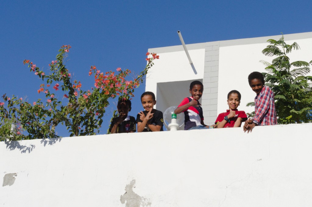 Дети на террасе белого дома с цветущим кустом