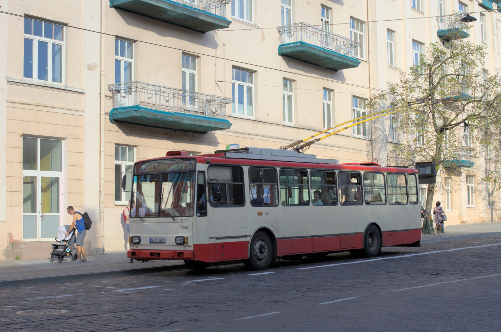 Троллейбус на фоне освещённого солнцем фасада