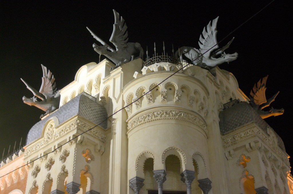 Ночной вид на фасад здания, на крыше четыре большие фигуры драконов