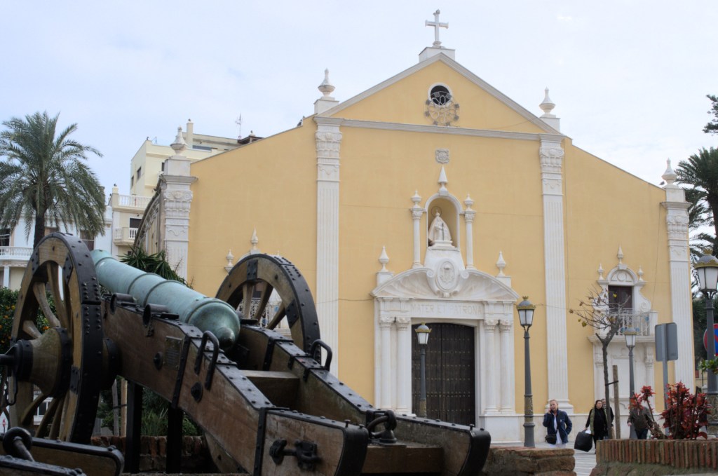 Жёлто-белый фасад церкви, на переднем плане старинная пушка