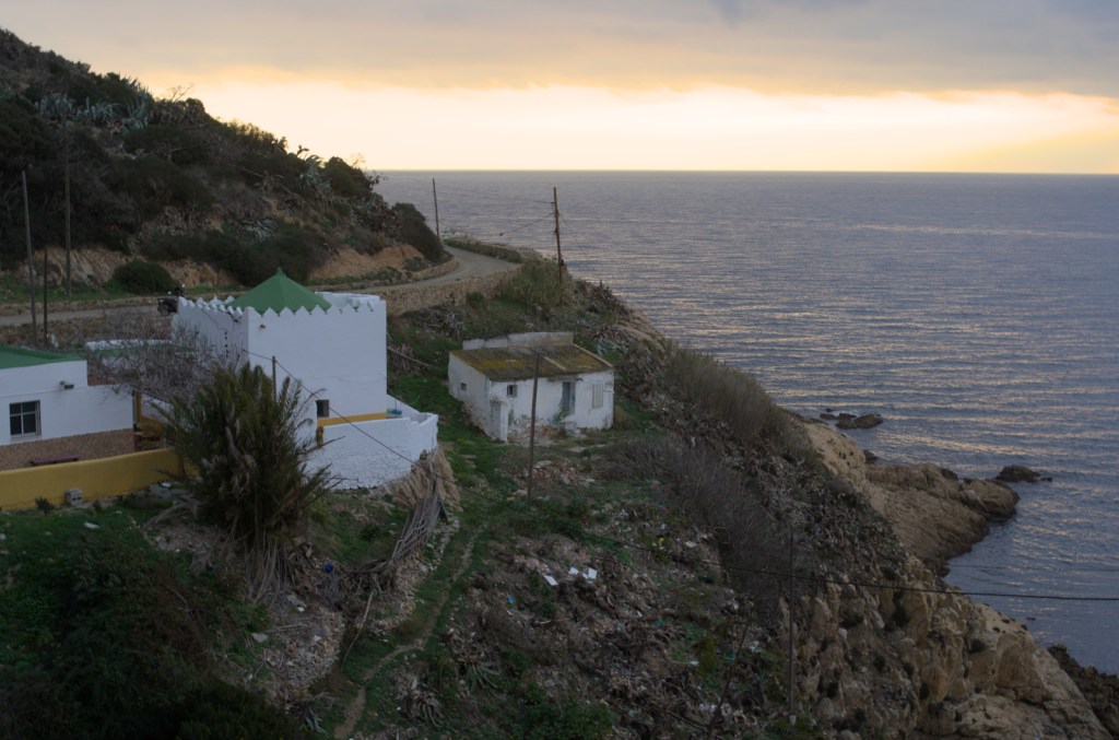 Белое здание мавзолея на скалистом берегу моря, рассветная заря